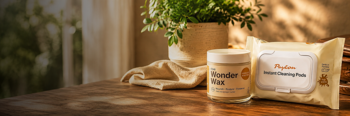 A jar of Wonder Wax and a package of Poplan Instant Cleaning Pads arranged on a wooden table next to a potted plant in a warm, sunlit interior setting.