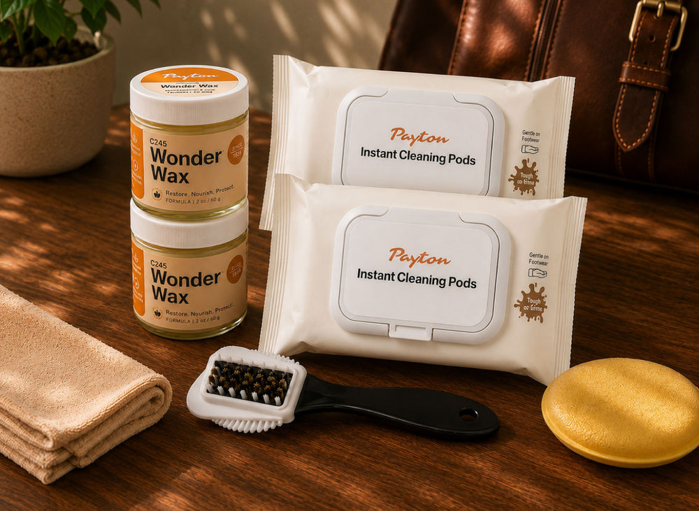 A product bundle on a wooden table featuring two jars of 'The Wonder Wax' natural hair wax, two packs of 'Peyton Instant Cleaning Pods', a beige towel, a black-handled brush, and a yellow sponge.