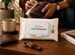 A pack of Payton Instant Cleaning Pods wipes in a white resealable pouch, placed on a wooden table in a real-world setting with a person in the background wiping a brown leather wallet.